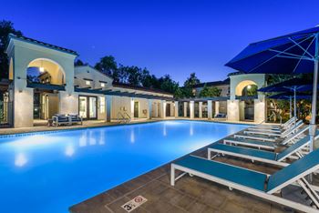 A swimming pool at night in front of a house
